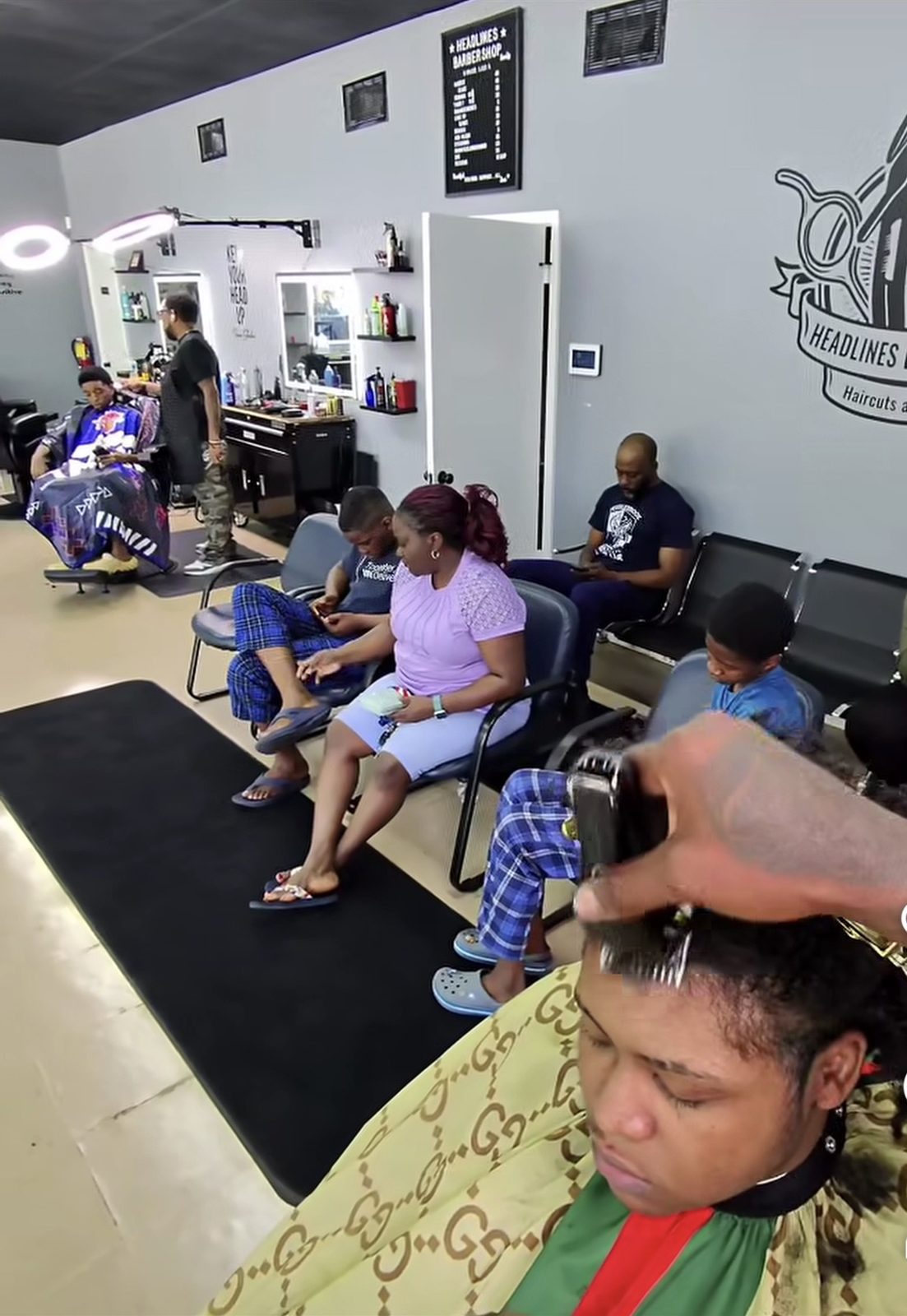 Clients waiting and barbers cutting on the Headlines Barbershop shop floor